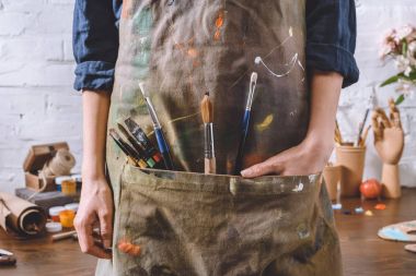 cropped image of artist with brushes and hand in apron pocket clipart