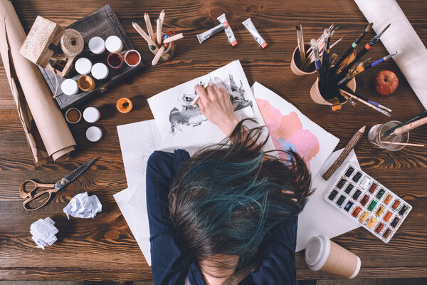 top view of female artist sleeping on sketches at workplace 