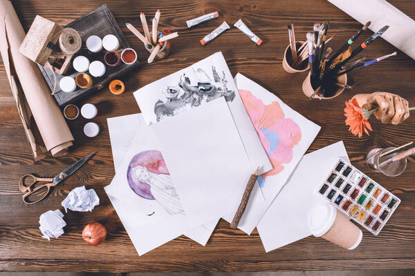 top view of designer workplace with sketches and paints