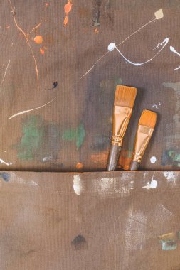 close-up view of brown apron with brushes and paint spots clipart