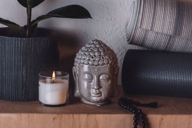 sculpture of buddha head and yoga mats on wooden shelf  clipart