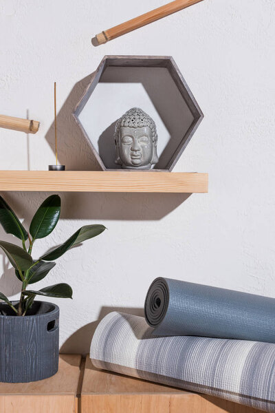sculpture of buddha head in frame and yoga mats