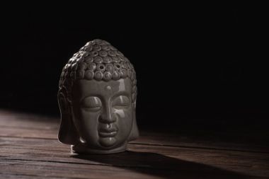 sculpture of buddha head on wooden table clipart