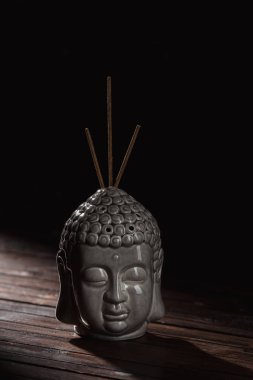 sculpture of buddha head with incense sticks clipart