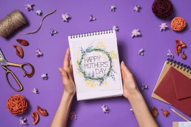 Kısmi mutlu tutan kadın görünümünü anneler günü kartpostal süslemeleri ile elinde mor üzerinde izole