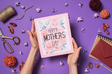 Kısmi mutlu tutan kadın görünümünü anneler günü kartpostal süslemeleri ile elinde mor üzerinde izole