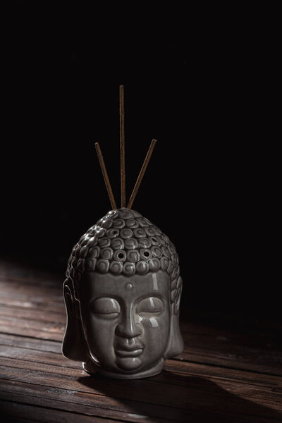 sculpture of buddha head with incense sticks