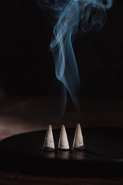 three burning incense sticks with smoke