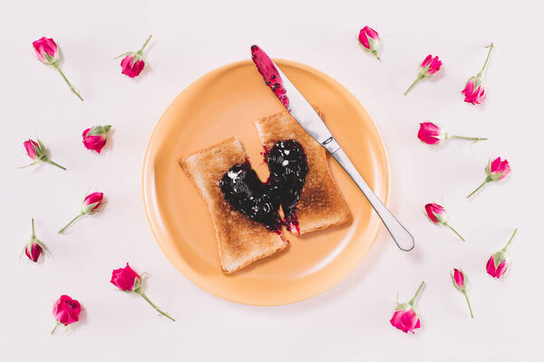 top view of toast with jam and knife on yellow plate isolated on white, valentines day concept