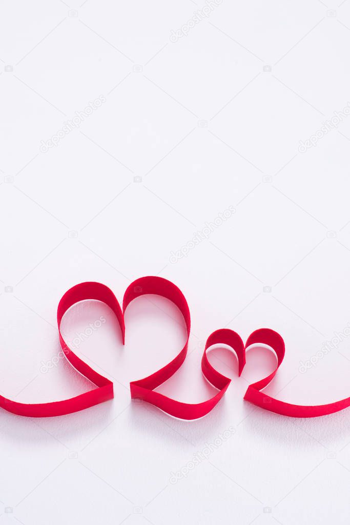 two red hearts from ribbon on white, valentines day concept