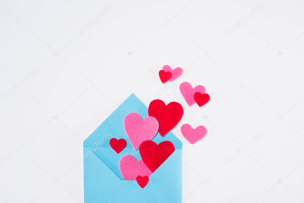 top view of blue envelope with paper hearts isolated on white, valentines day concept