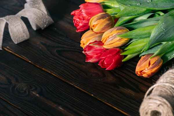 close up view of bouquet of tulips, ribbon and rope on wooden tabletop