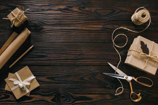 плоский укладывается с обернутыми подарками, веревкой и ножницами на деревянной поверхности

