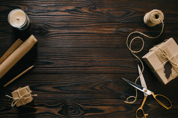 flat lay with wrapped presents, rope and scissors on wooden surface