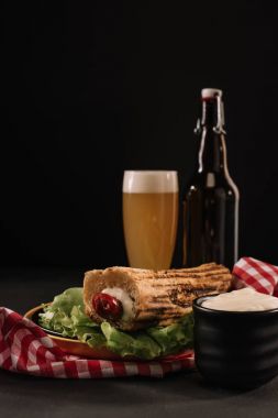 lezzetli Fransız hot dog'şişe ve bardak siyah izole bira ile plaka