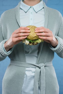 Yeşil vejetaryen burger tutan kadın görüntüsünü kırpılmış
