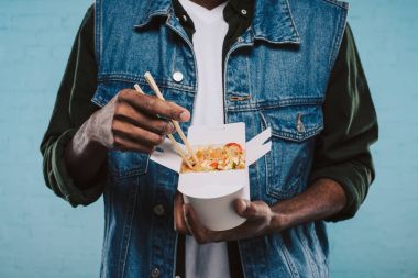 cropped shot of african american man holding box of asian noodles clipart