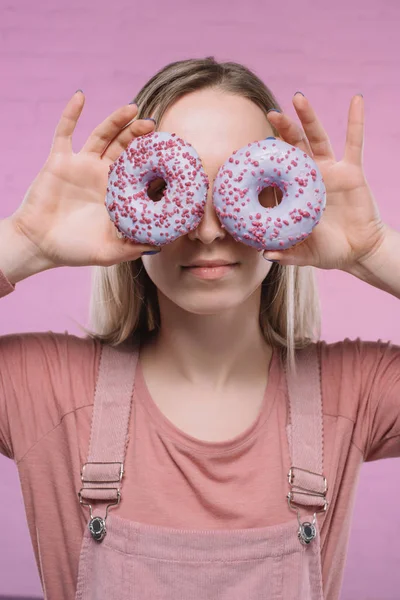 有魅力的年轻妇女用甜甜圈遮住眼睛 — 图库照片