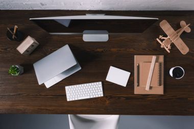 İşyerinde masaüstü bilgisayar, dizüstü bilgisayar ve ofis malzemeleri Üstten Görünüm