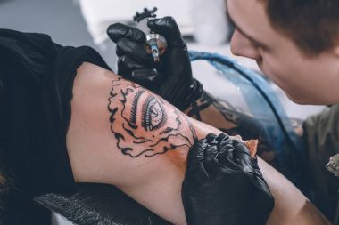 Tattoo artist in gloves working in studio clipart