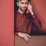 Rozważny człowiek trzyma telefon słuchawki przez ściany czerwony papier na czarnym tle