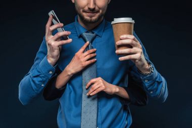 Telefon ve mavi izole kahve ile işadamı kravat sabitleme eller