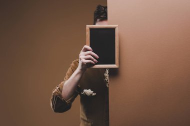 Adam boş çerçeve izole kahverengi üzerine tutarak şık giysiler