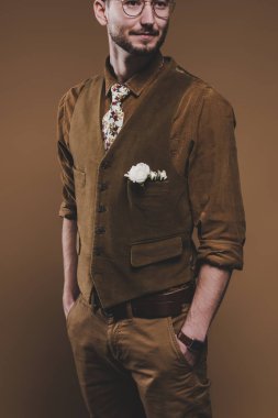 Vintage tarzı giysiler izole kahverengi üzerine yaka çiçeği ile genç adam