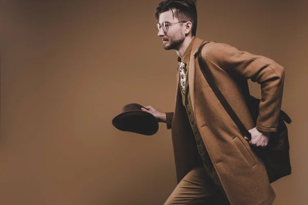 Young Man Coat Holding Hat Running Isolated Brown — Stock Photo, Image