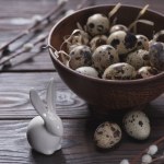 Easter quail eggs in bowl with straw on table