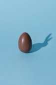 Jeden čokoládový velikonoční vajíčko s bunny stín na modré ploše