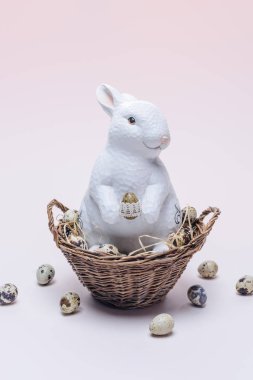 Ester bunny bıldırcın yumurtası ve sepet üzerinde bej saman ile