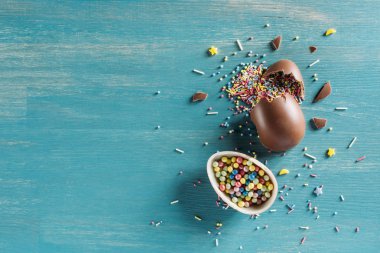 top view of broken chocolate easter eggs on wooden turquoise table clipart