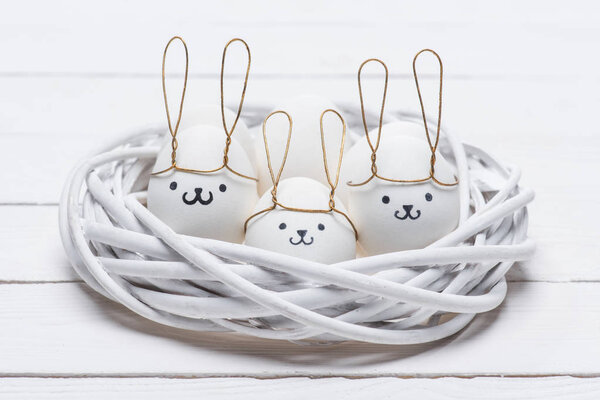 пасхальные куриные яйца с улыбками и кроличьи уши в гнезде
