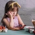 Entzückendes Kind blickt auf bemaltes Osterei in der Hand