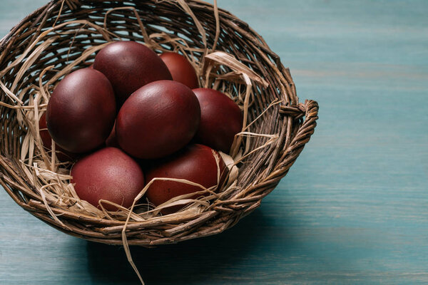 easter basket with painted eggs and straw on table