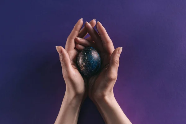 Обрізане Зображення Жінки Тримає Розфарбоване Пасхальне Яйце Над Фіолетовою Поверхнею — стокове фото