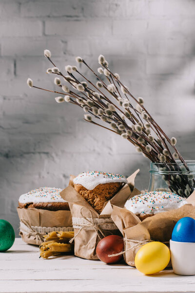 easter bread, painted eggs, catkins and candles on wooden table