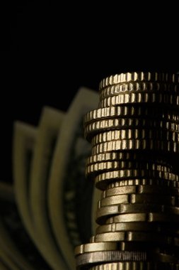 selective focus of stack of coins and banknotes isolated on black clipart