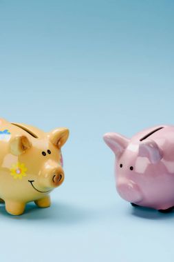 close up view of two yellow and pink piggy banks isolated on blue clipart