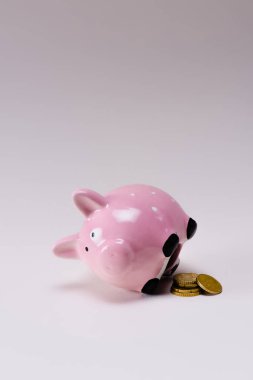 close up view of pink piggy bank and pile of coins isolated on lilac clipart