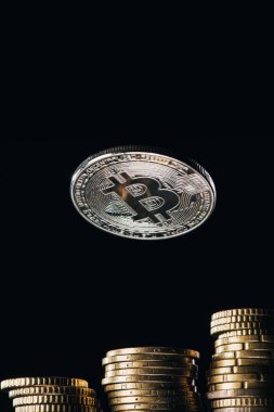Close up view of silver bitcoin and stacks on cents isolated on black clipart