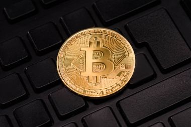 Close up view of golden bitcoin in black keyboard clipart