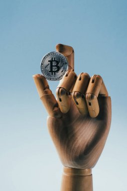 Mavi üzerinde izole gümüş bitcoin tutan ahşap kukla el yakından görünümü