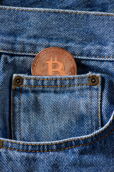 Close up view of bronze bitcoin in denim pocket