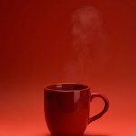 Закрытый вид красной чашки кофе, изолированной на красной