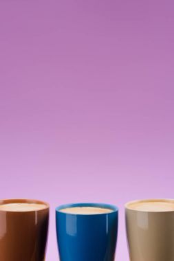 close up view of arranged colorful cups of coffee isolated on purple clipart