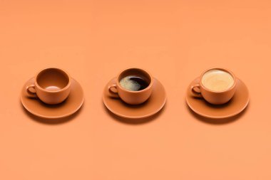 close up view of arrangement of empty cup and two cups of coffee isolated on peach clipart
