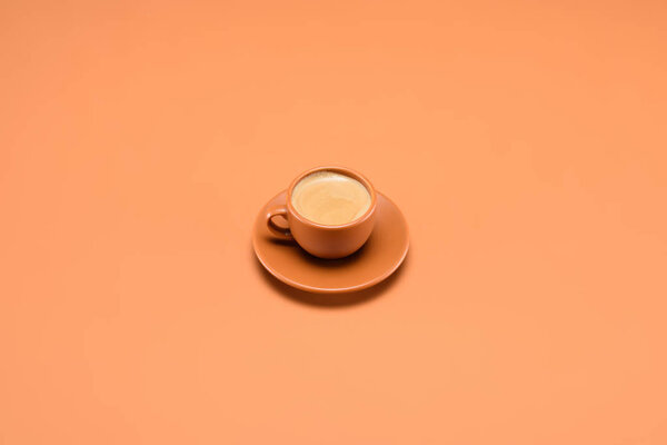 close up view of cup of coffee on saucer isolated on peach