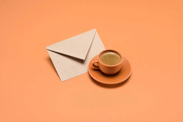 コーヒー カップのソーサーとピーチに分離された封筒にビューをクローズ アップ — ストック写真